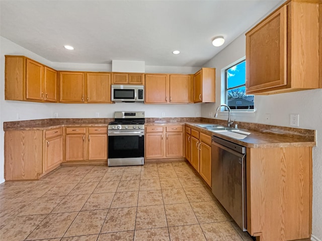 kitchen featuring dark countertops, light tile patterned floors, recessed lighting, stainless steel appliances, and a sink