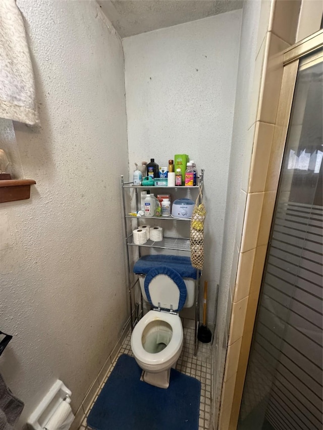 bathroom featuring a shower stall, toilet, and a textured wall