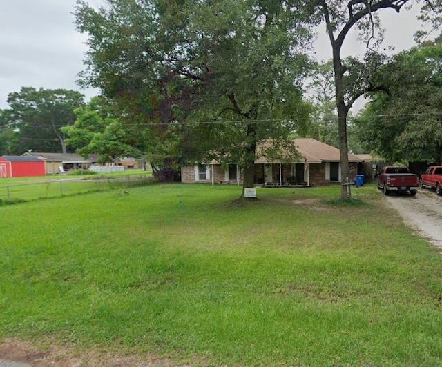 view of front of home featuring driveway, a front lawn, and fence