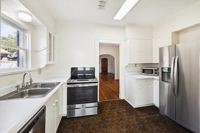 kitchen featuring visible vents, arched walkways, a sink, light countertops, and appliances with stainless steel finishes