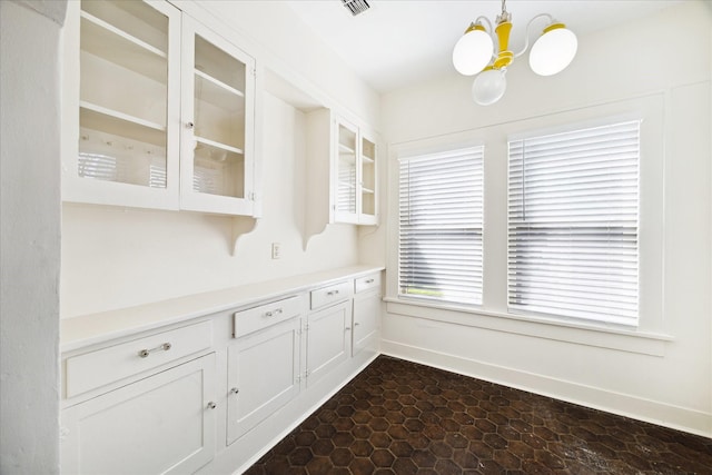 kitchen featuring light countertops, pendant lighting, glass insert cabinets, and a chandelier