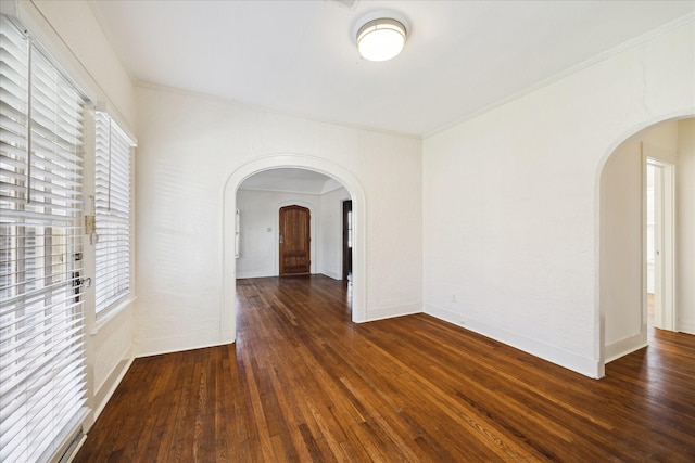 unfurnished room featuring baseboards, arched walkways, and hardwood / wood-style flooring