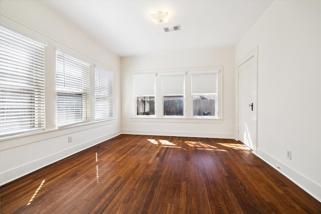 unfurnished room with visible vents, baseboards, and hardwood / wood-style flooring