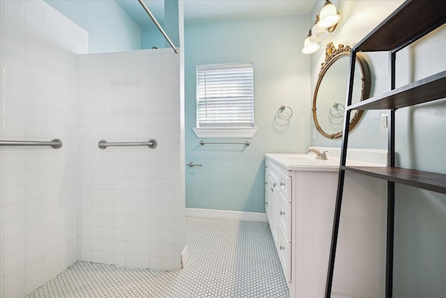 full bath featuring vanity, baseboards, and a tile shower