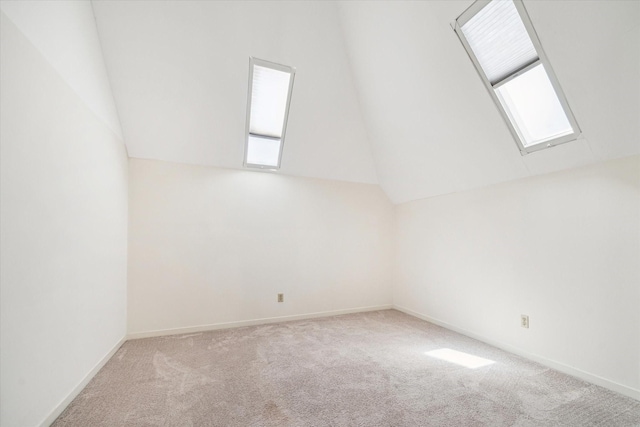 additional living space with vaulted ceiling with skylight, carpet flooring, and baseboards