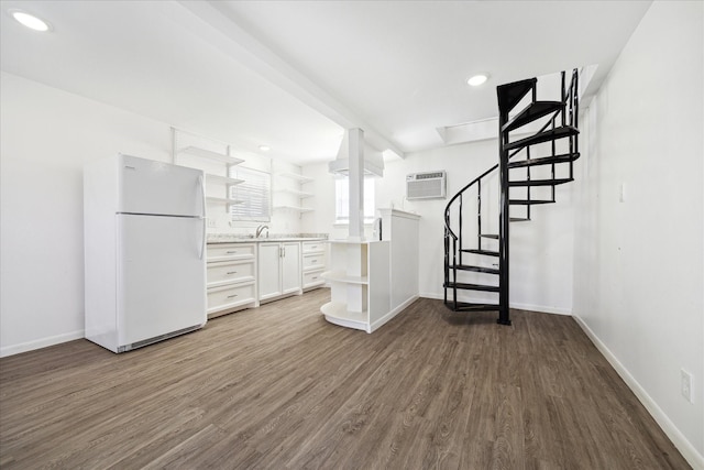 interior space with dark wood-style floors, baseboards, freestanding refrigerator, and a wall mounted AC