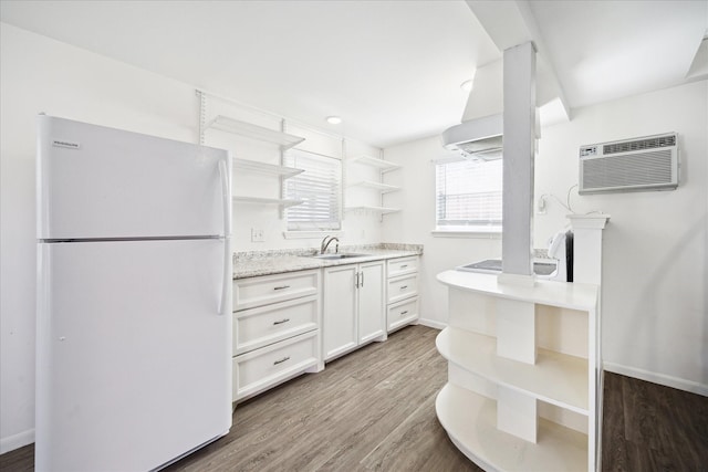 kitchen featuring an AC wall unit, light wood-style flooring, open shelves, freestanding refrigerator, and stovetop