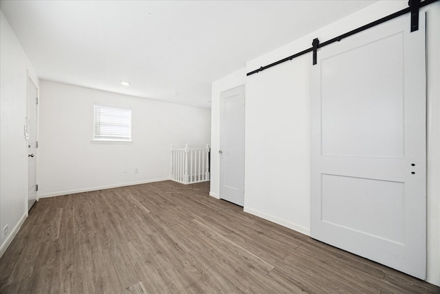 interior space with a barn door, wood finished floors, and baseboards