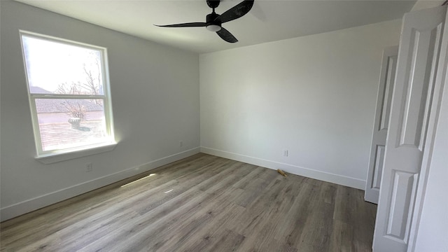 empty room featuring ceiling fan, baseboards, and wood finished floors