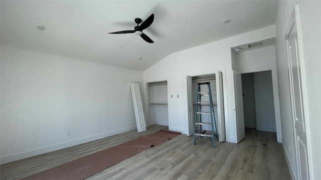 unfurnished bedroom with visible vents, lofted ceiling, wood finished floors, baseboards, and ceiling fan