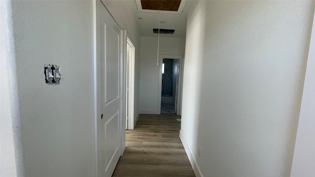 corridor with visible vents, baseboards, attic access, and wood finished floors