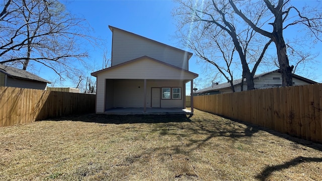 rear view of house with a patio, a fenced backyard, and a lawn