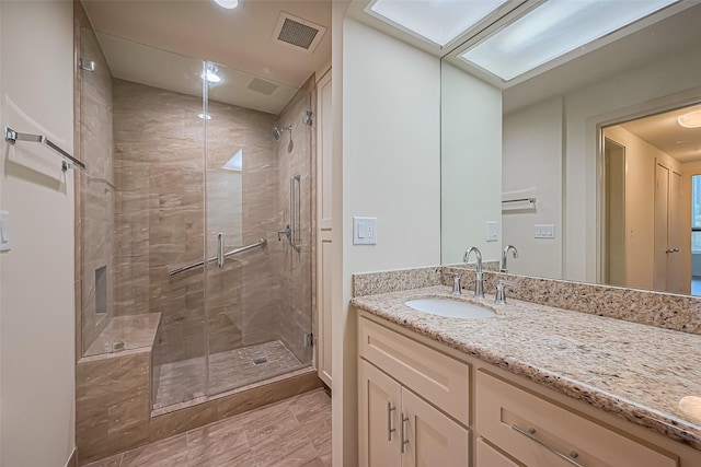 bathroom featuring visible vents, vanity, a skylight, and a shower stall