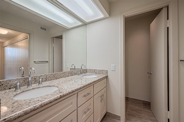 bathroom featuring double vanity, baseboards, visible vents, and a sink