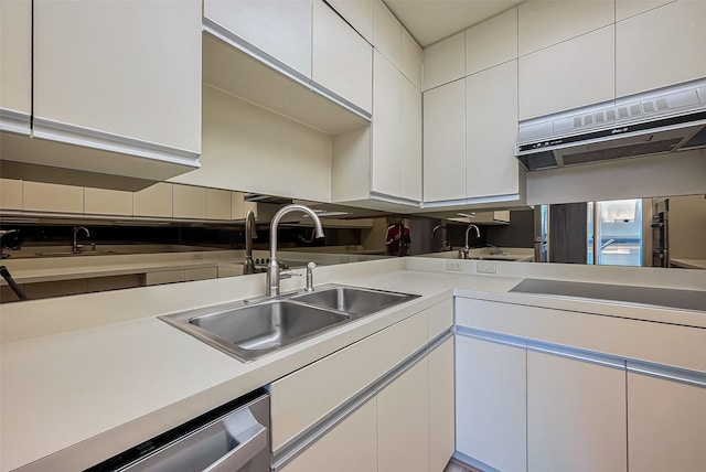 kitchen with under cabinet range hood, white cabinetry, light countertops, and a sink