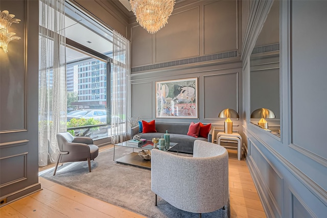 living area featuring a decorative wall, a notable chandelier, and light wood finished floors