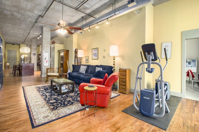 living room with wood finished floors, baseboards, a towering ceiling, and ceiling fan