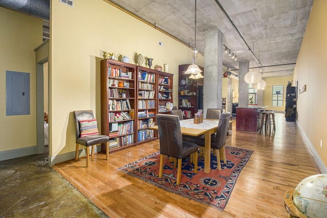 dining area featuring visible vents, track lighting, electric panel, wood finished floors, and baseboards