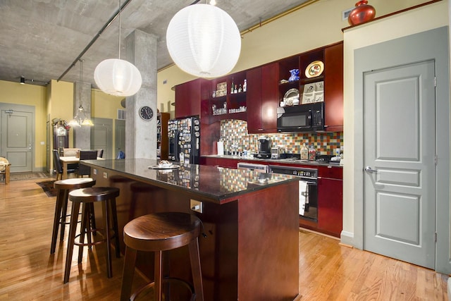 kitchen featuring dark countertops, dark brown cabinets, black appliances, and light wood-style floors