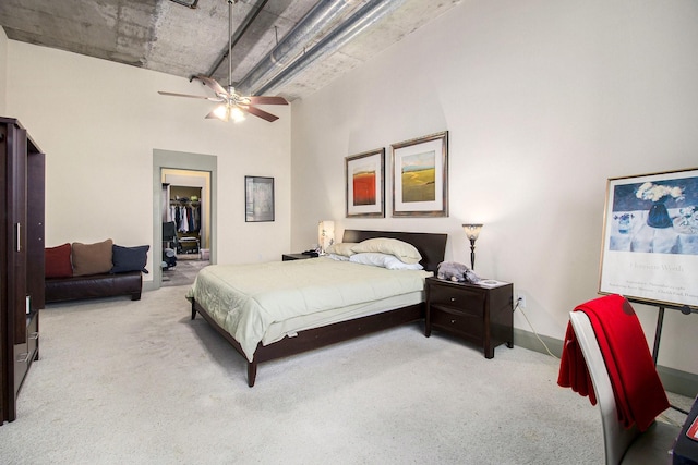 bedroom with a walk in closet, carpet, a towering ceiling, a closet, and a ceiling fan