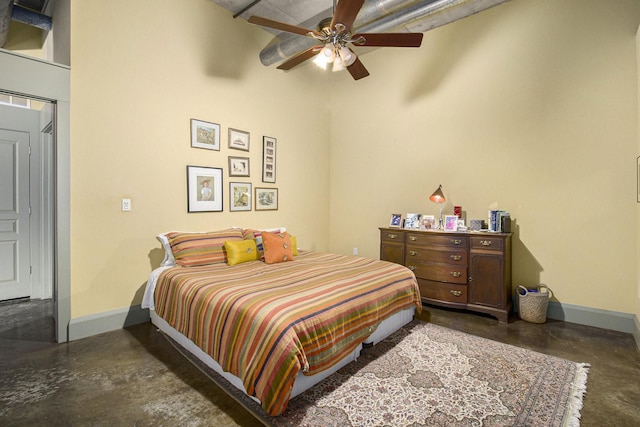 bedroom featuring a high ceiling, finished concrete flooring, baseboards, and ceiling fan