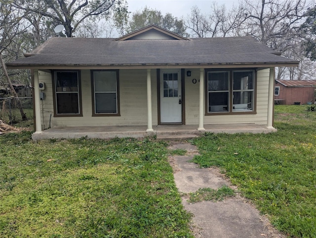 bungalow-style house with a porch, a front lawn, and a shingled roof