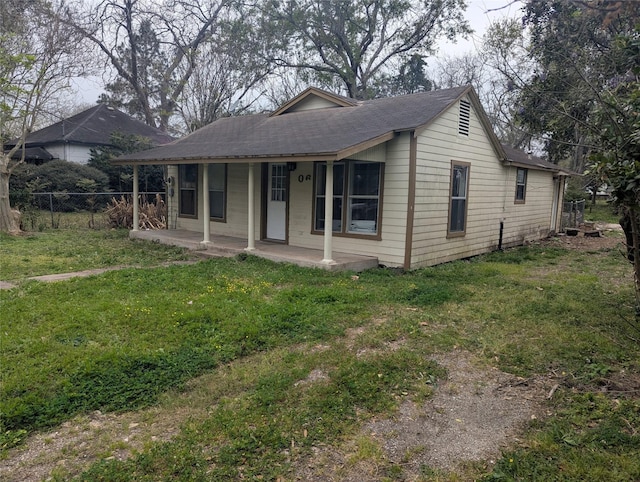 rear view of house featuring covered porch, fence, a lawn, and roof with shingles