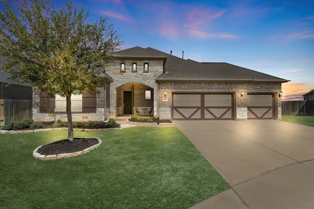 view of front of property with a garage, stone siding, a yard, and fence