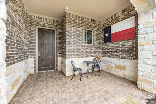 property entrance featuring crawl space, a patio, and brick siding