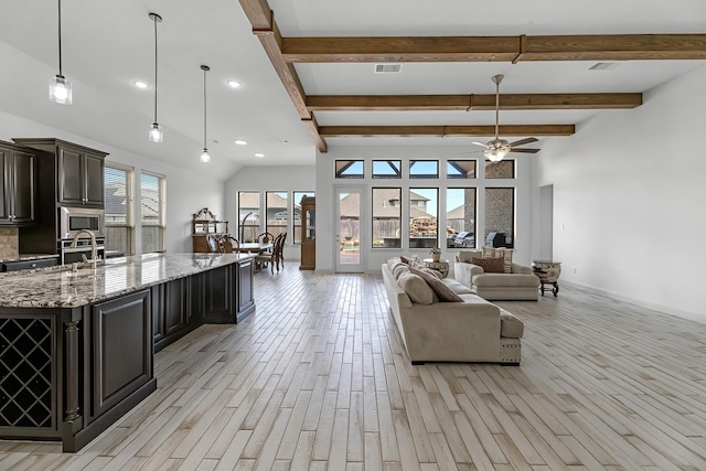 interior space featuring ceiling fan, open floor plan, light wood-type flooring, stainless steel appliances, and a sink