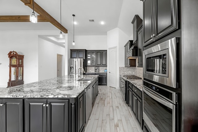 kitchen featuring visible vents, a large island, a sink, backsplash, and stainless steel appliances