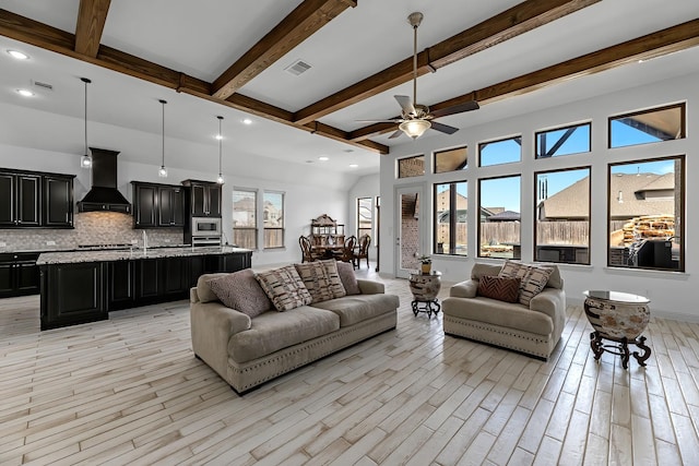 living area featuring beamed ceiling, visible vents, light wood finished floors, and ceiling fan