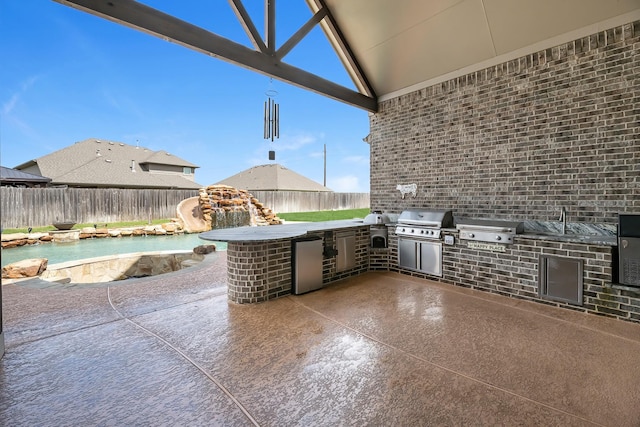 view of patio featuring grilling area, a fenced backyard, and exterior kitchen