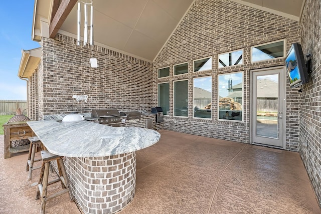 view of patio featuring outdoor wet bar, area for grilling, a grill, and fence