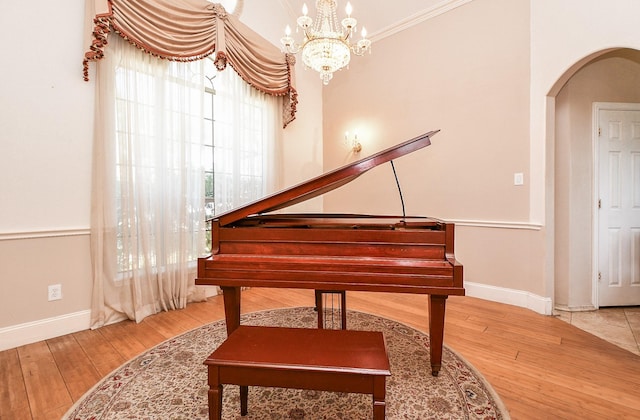 sitting room featuring a chandelier, arched walkways, baseboards, and wood-type flooring