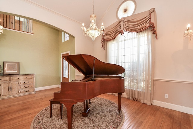 living area with a notable chandelier, arched walkways, light wood-type flooring, and baseboards