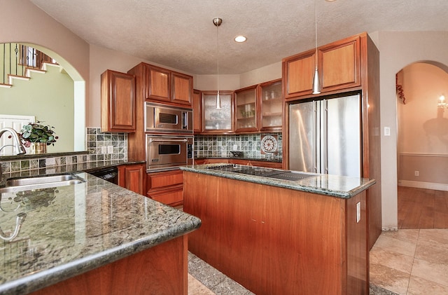 kitchen featuring a sink, arched walkways, black appliances, and brown cabinetry