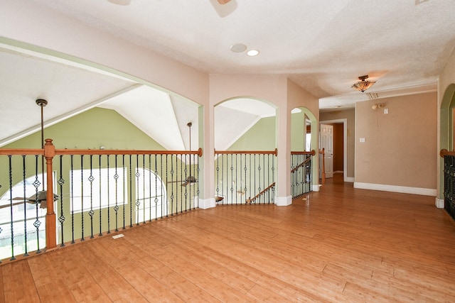 spare room featuring lofted ceiling, a ceiling fan, baseboards, and wood-type flooring