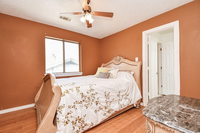 bedroom featuring ceiling fan, light wood-style floors, visible vents, and baseboards