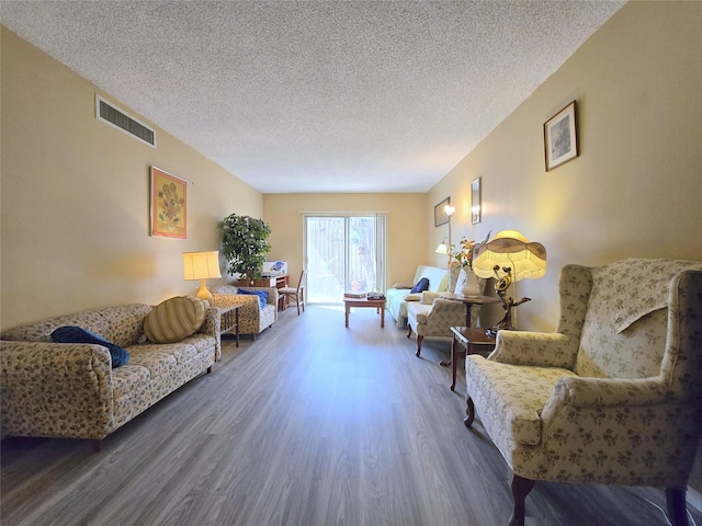 living area with visible vents, a textured ceiling, and wood finished floors