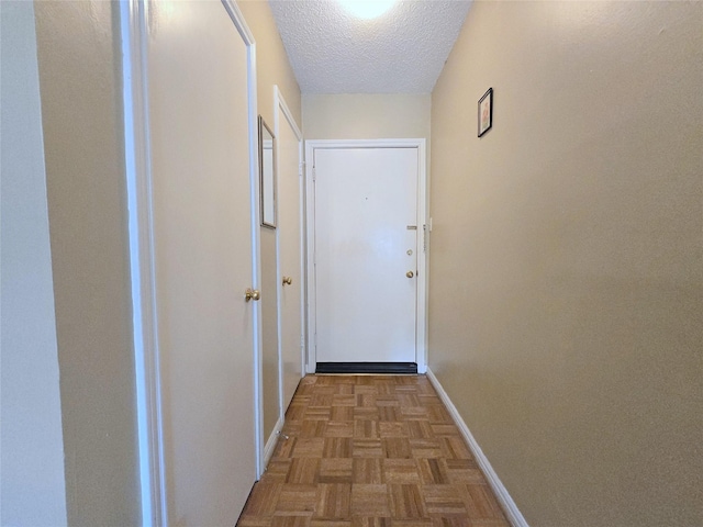 doorway to outside with a textured ceiling and baseboards