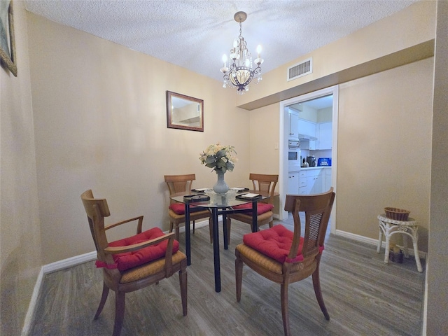 dining space featuring visible vents, baseboards, an inviting chandelier, and wood finished floors