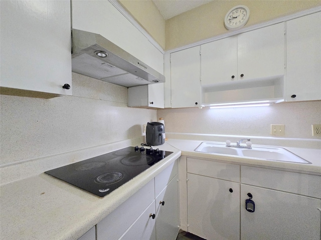 kitchen with black electric stovetop, white cabinets, and under cabinet range hood