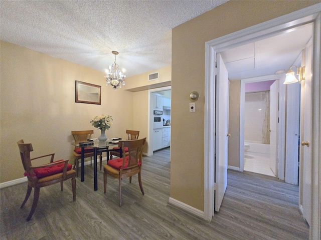 dining space featuring an inviting chandelier, baseboards, dark wood-style flooring, and a textured ceiling