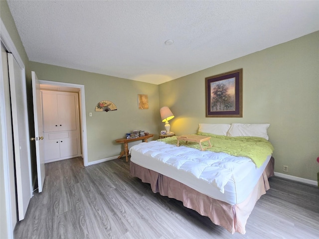 bedroom featuring wood finished floors, baseboards, and a textured ceiling