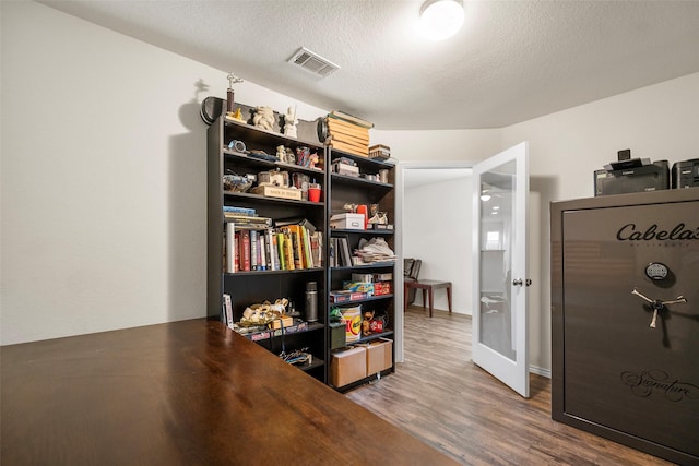 office with wood finished floors, visible vents, and a textured ceiling