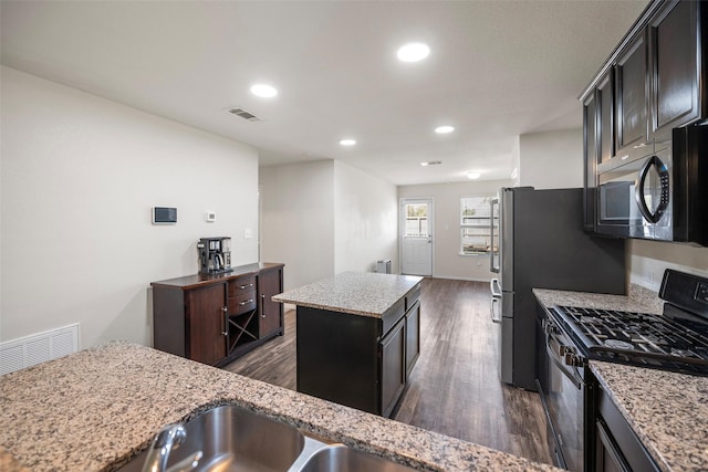 kitchen featuring visible vents, dark wood-style floors, a center island, and black gas stove