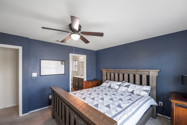 carpeted bedroom featuring visible vents, ceiling fan, baseboards, ensuite bathroom, and a textured wall