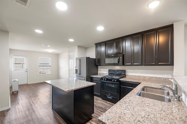 kitchen featuring visible vents, a sink, a kitchen island, black appliances, and dark wood-style flooring