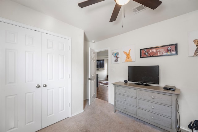 bedroom with visible vents, a ceiling fan, a closet, baseboards, and light colored carpet